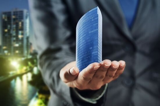 homme tenant un immeuble miniature dans la main